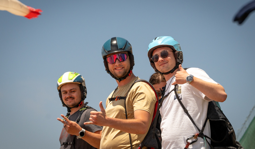 Three people wearing helmets smile by giving a thumbs up on a sunny day in Tenerife.