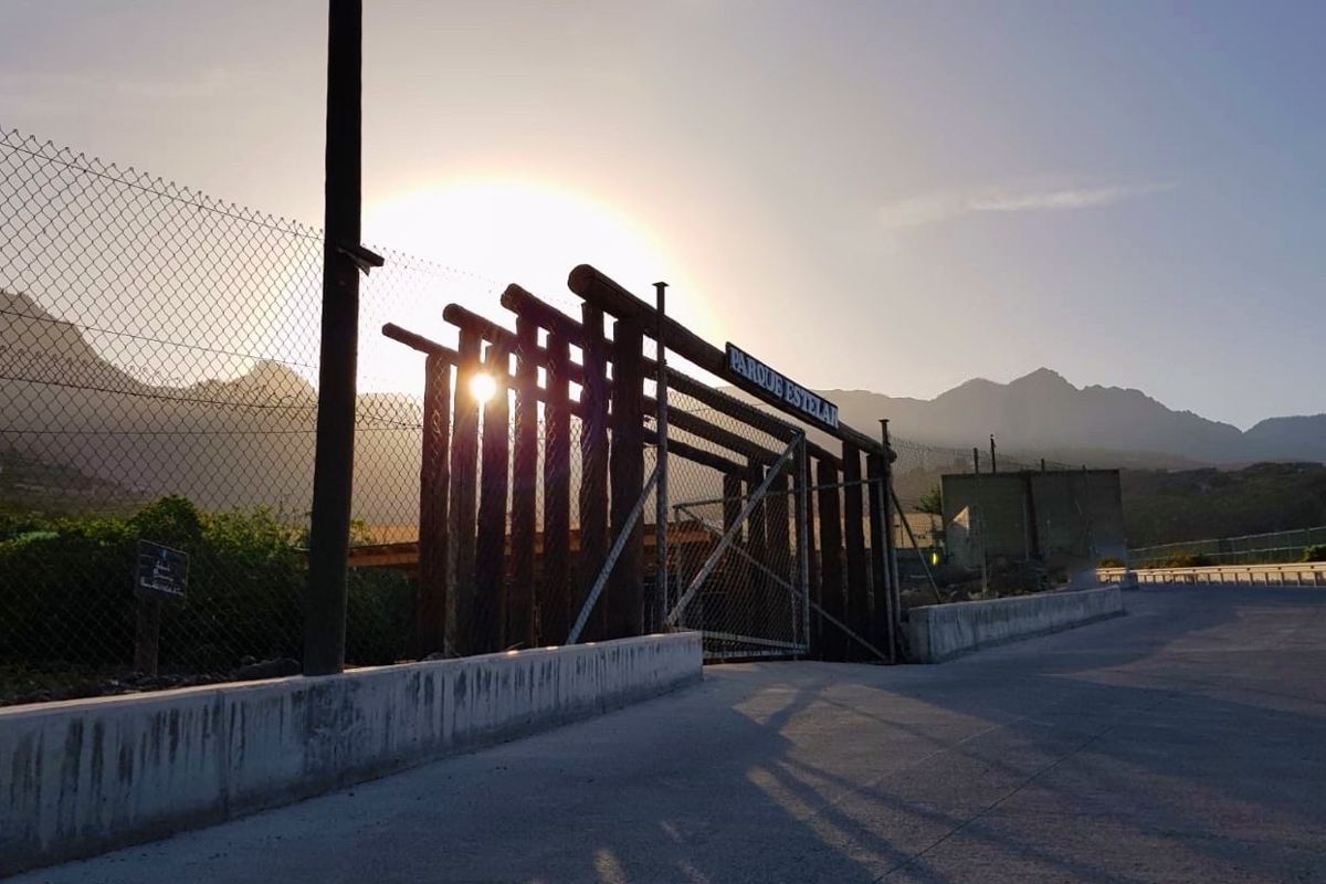 Fenced entrance to the Parque Estelar de Tenerife with mountains in the background and the sun shining.