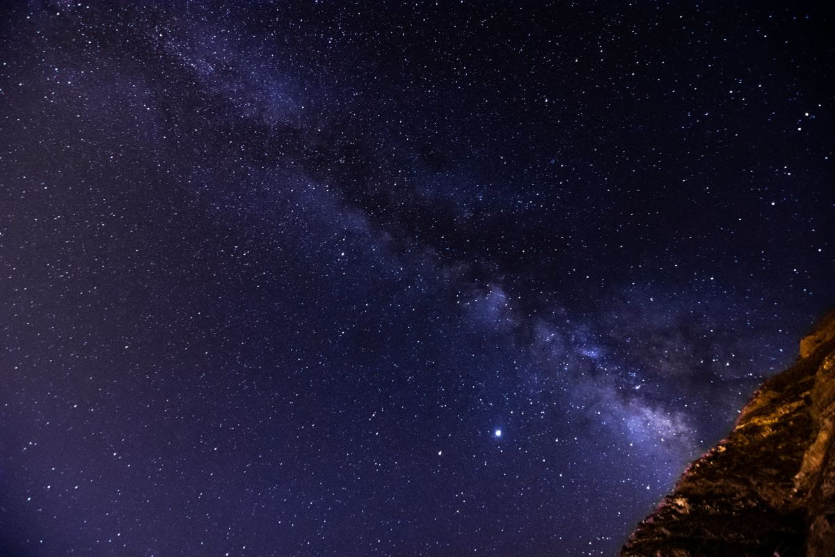 Starry sky with the Milky Way visible over a rocky landscape in Tenerife.
