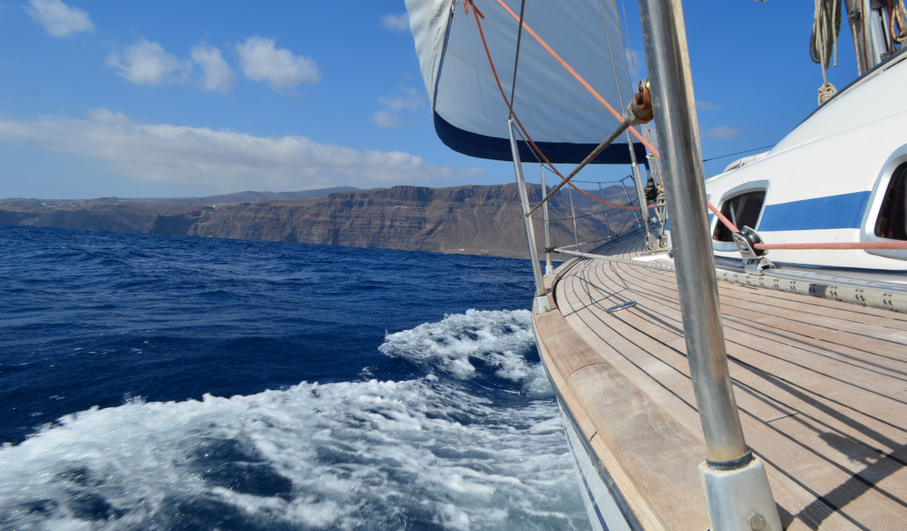 Sailboat sailing near the coast of Tenerife with mountains in the background.