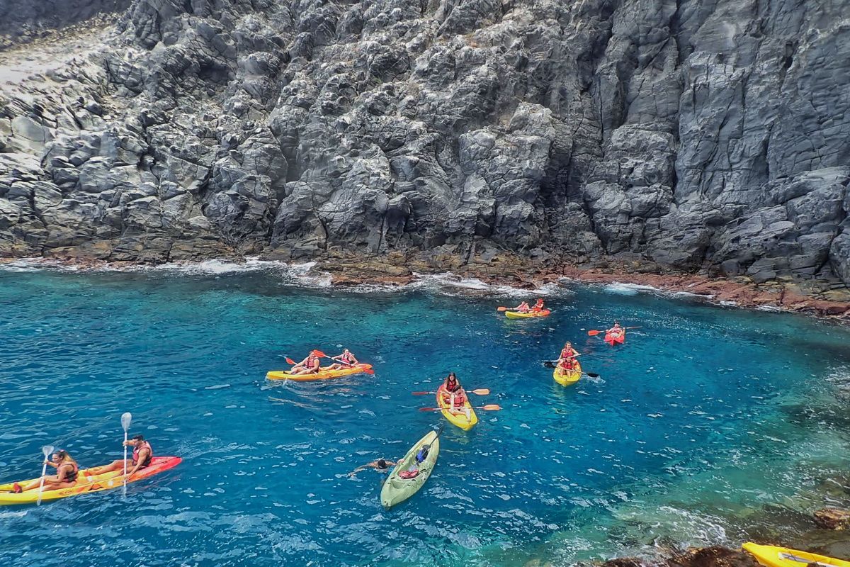 Kayaks in the crystal clear water next to cliffs in Tenerife.