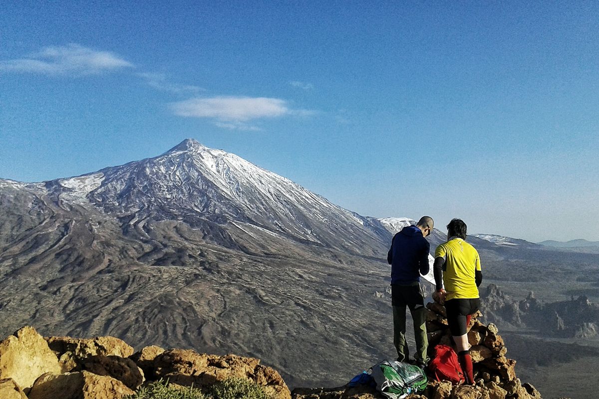 Two people standing at a viewpoint overlooking the Teide volcano in Tenerife.