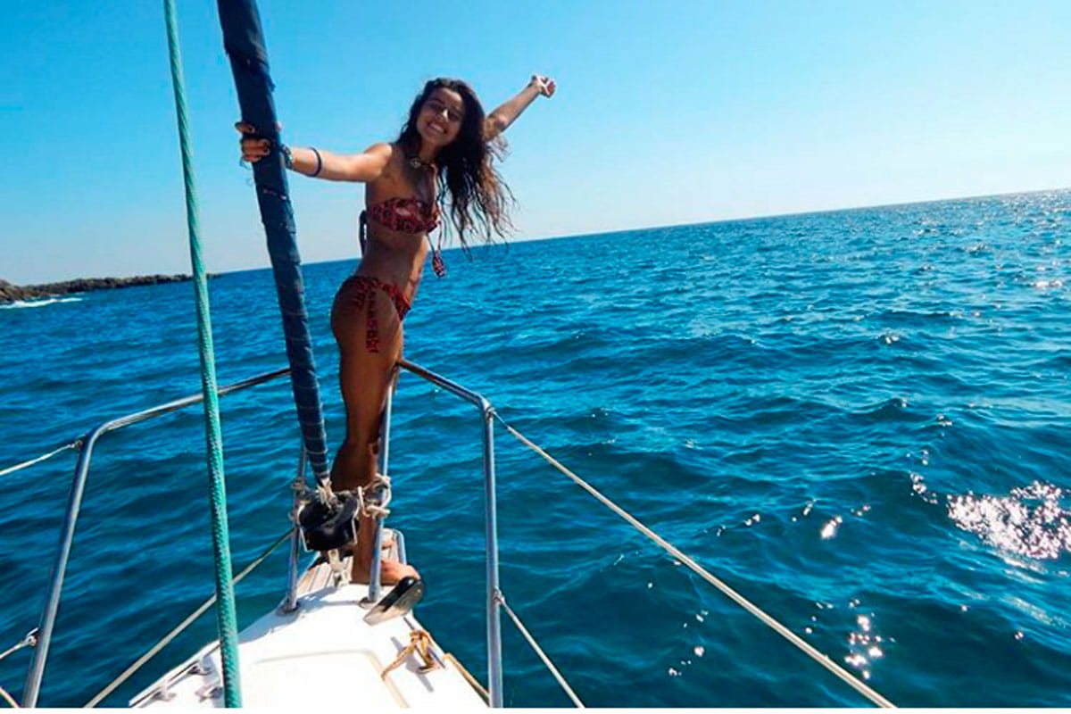 Person in bikini enjoying on the bow of a boat at sea near Tenerife.