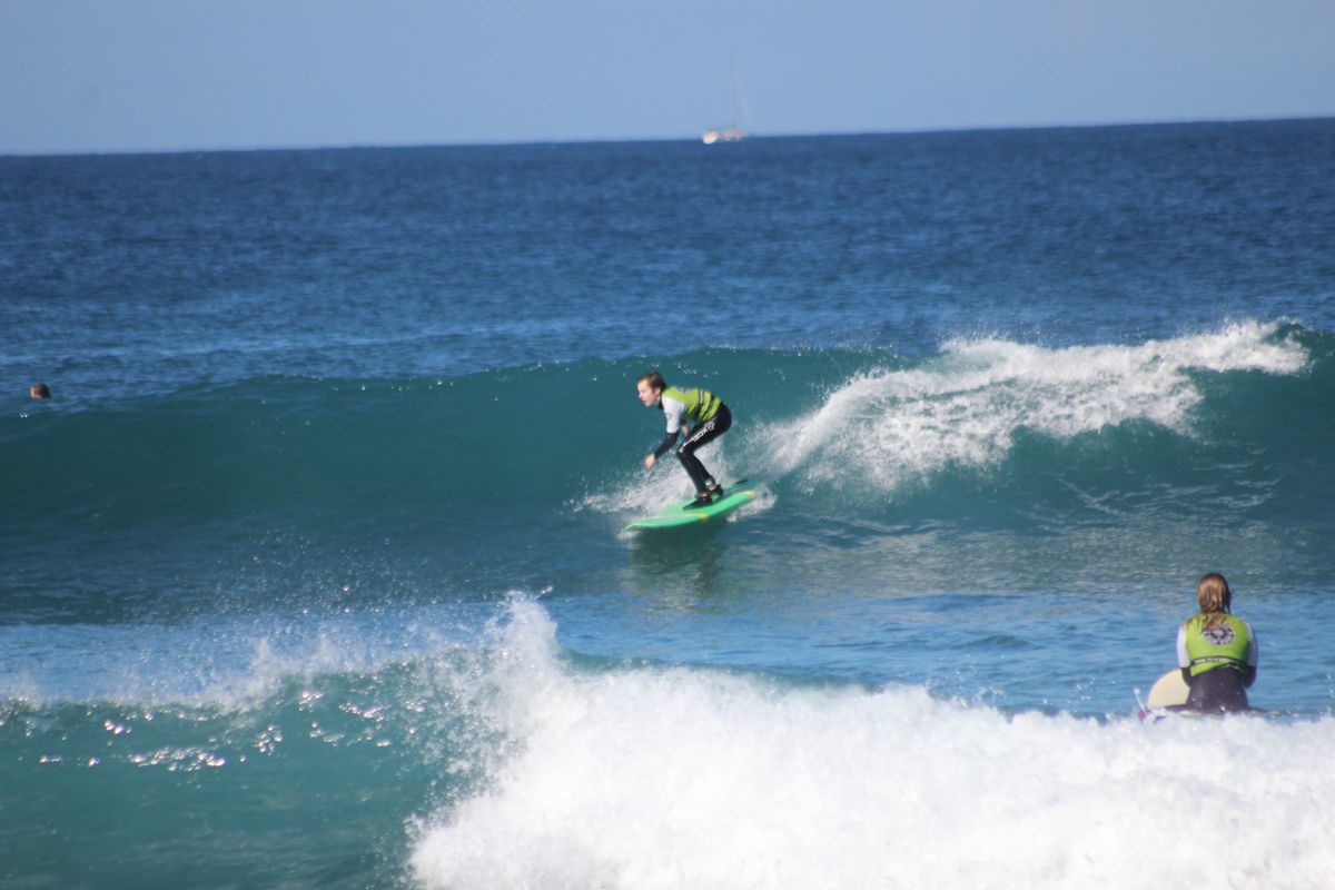 Surfer riding a wave in Tenerife, with another person watching from the water.