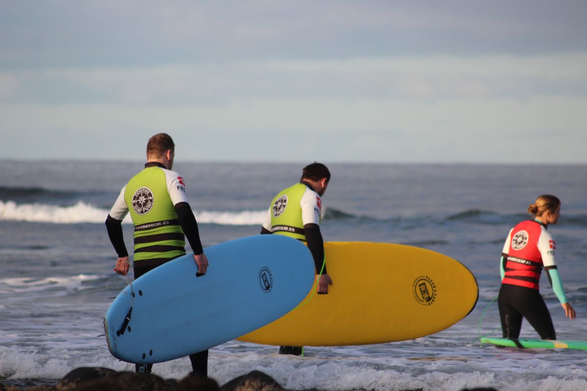 Surfers entering the sea with colorful boards in Tenerife.