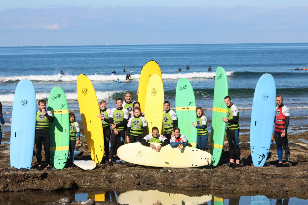 Group of surfers with colored boards on the beach of Tenerife.