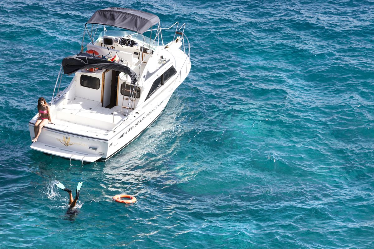 Boat with young man on board and person diving in the sea of Tenerife.