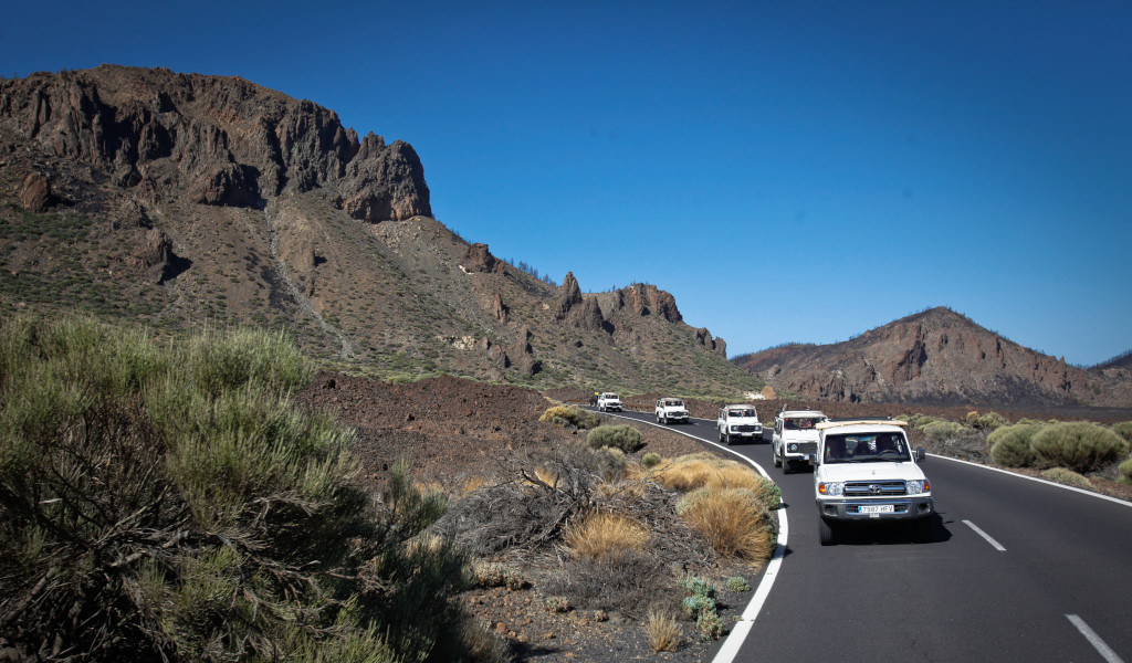Caravan of cars on the road to Mount Teide, Tenerife, surrounded by mountains.