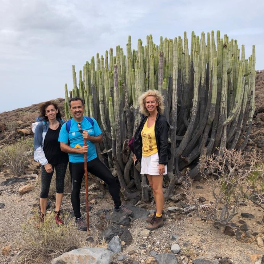 Three people next to a large cactus in a rocky environment in Tenerife.
