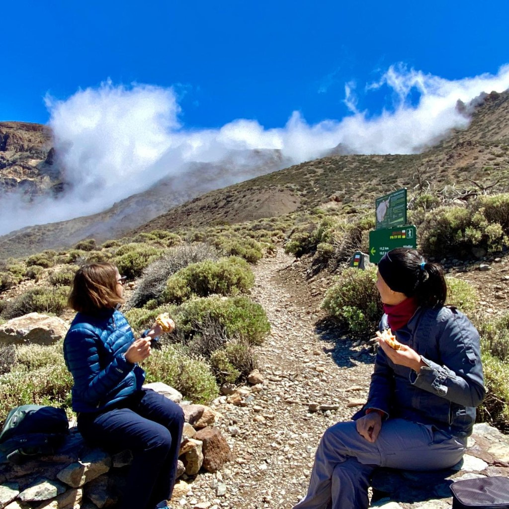 People sitting eating on a trail in Teide National Park, Tenerife.