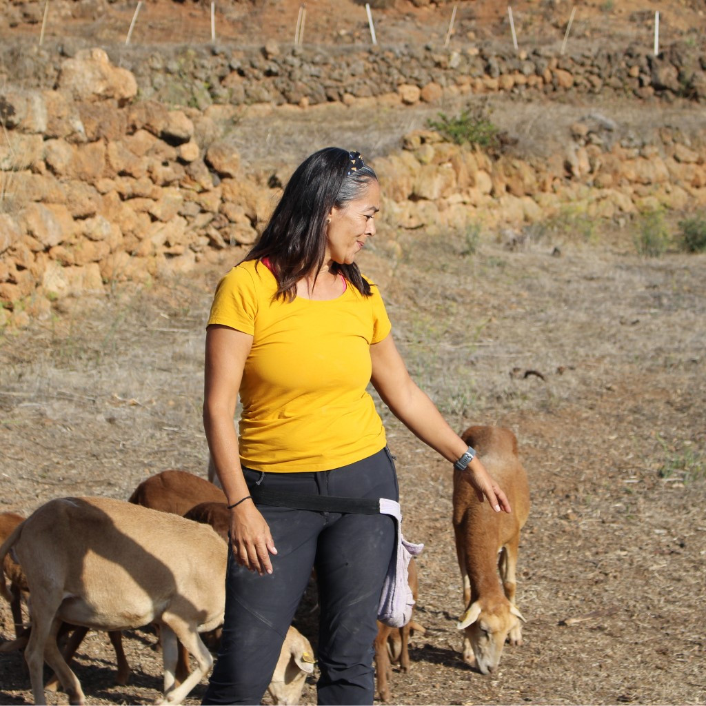 Woman next to goats grazing on a rural plot of land in Tenerife.