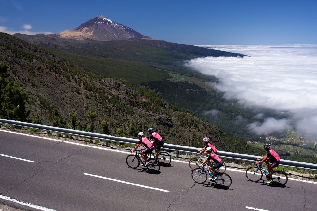 Cyclists climbing near Mount Teide in Tenerife with views of the valley and the sea of clouds.