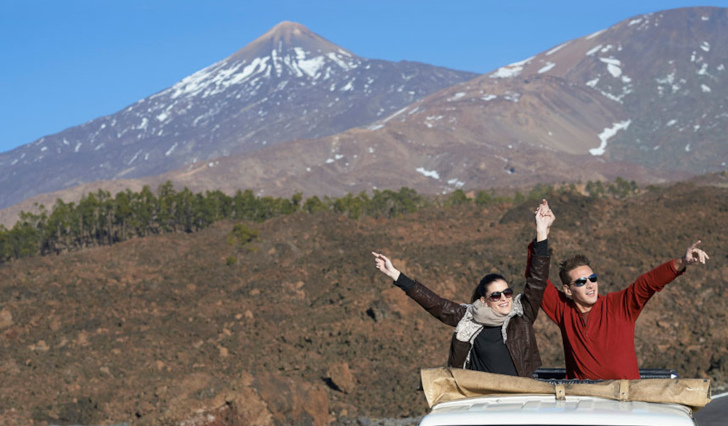 Smiling people in a jeep in front of Mount Teide in Tenerife.