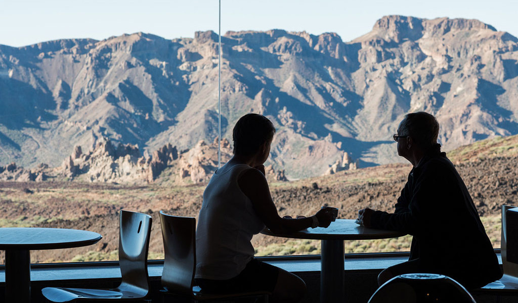 Two people sitting in a café overlooking the Teide National Park, Tenerife.