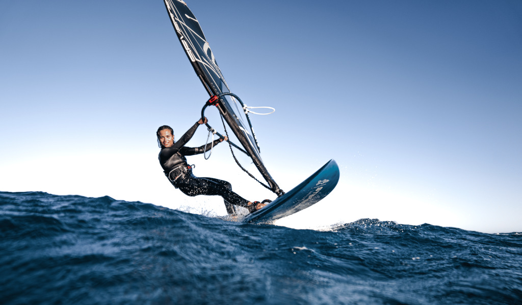 Person windsurfing in the sea near Tenerife under a clear sky.