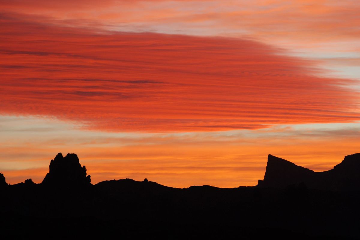 Sunset over mountains in Tenerife with red clouds and orange sky.