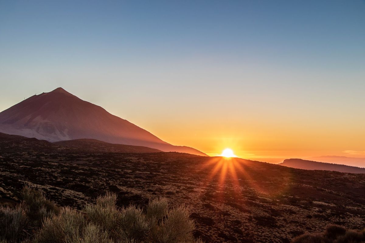 Sunrise on Mount Teide, Tenerife, with the sun peeking out from behind the horizon.