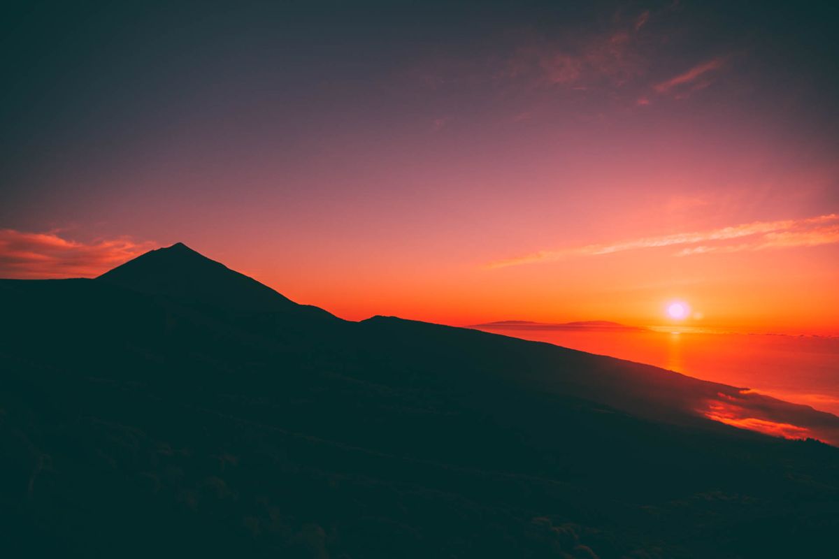 Sunrise over Mount Teide in Tenerife with red skies and sun on the horizon.