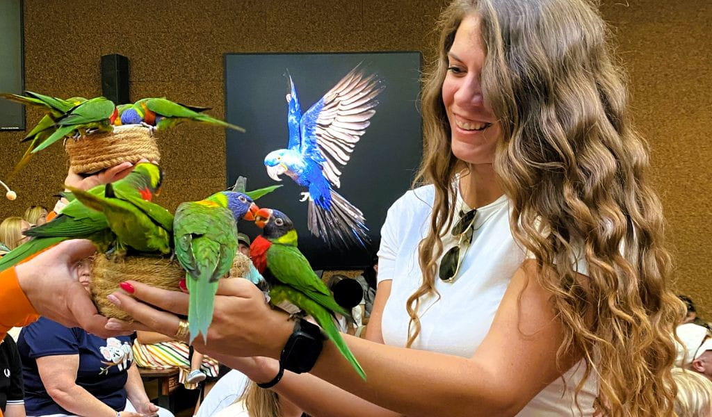 Woman holding several parrots in Loro Parque in Tenerife.