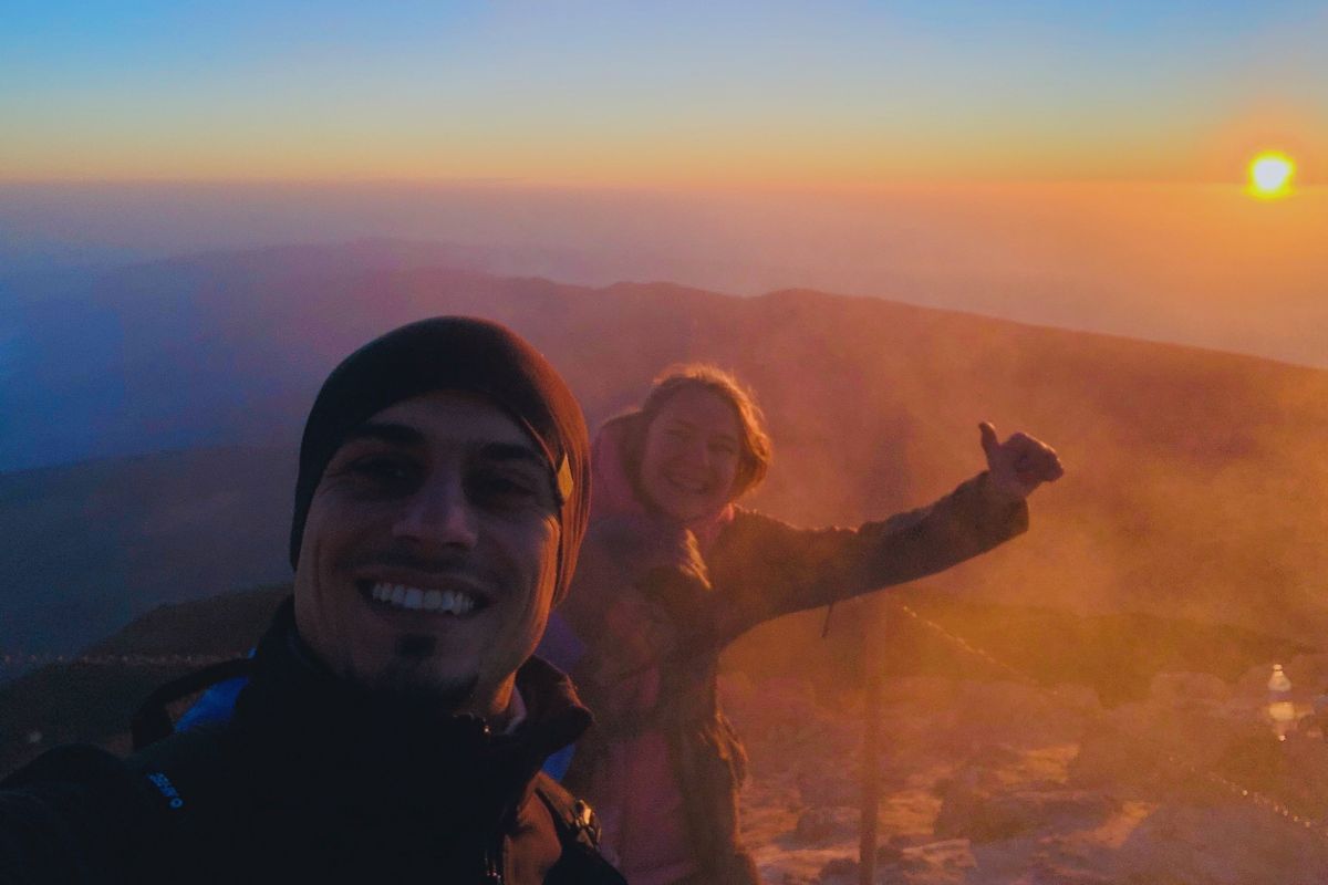 People smiling at dawn on Mount Teide, Tenerife, with the sun in the background.