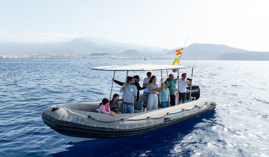 People on a boat in the sea near Tenerife with mountains in the background.