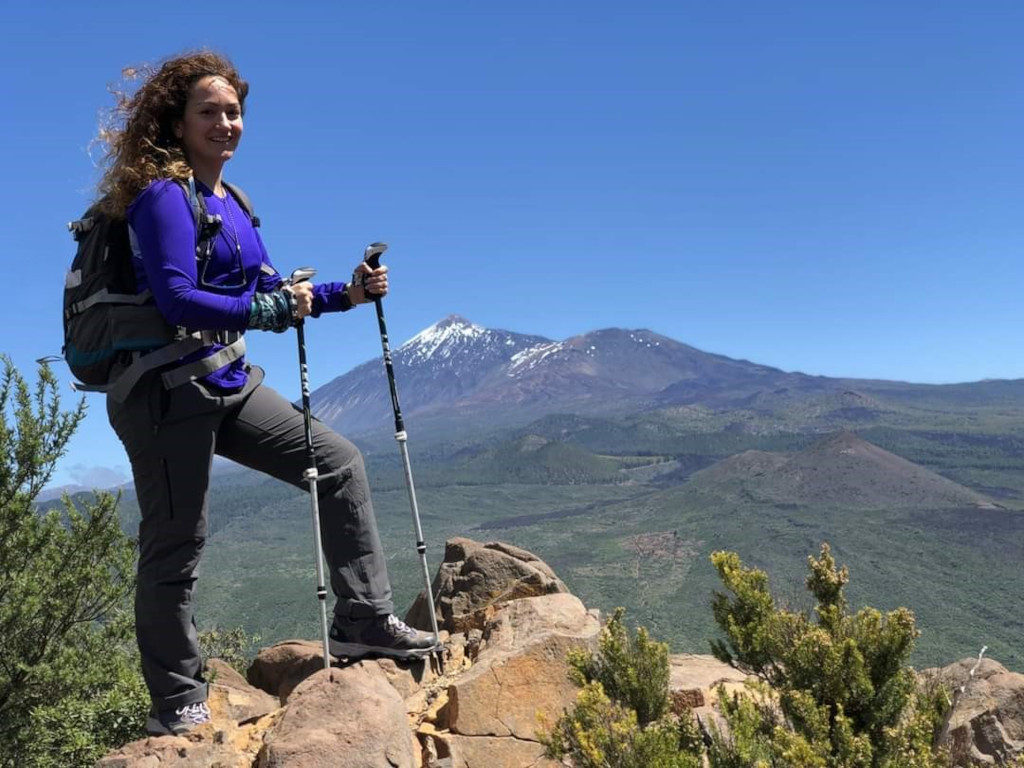 Hiker with poles on a rocky path with Mount Teide in the background, Tenerife.