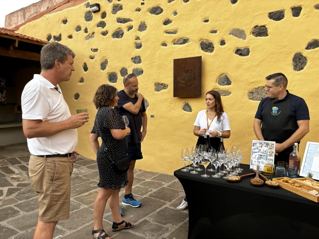 Group of people at wine tasting in Tenerife, next to a table with drinks and snacks.