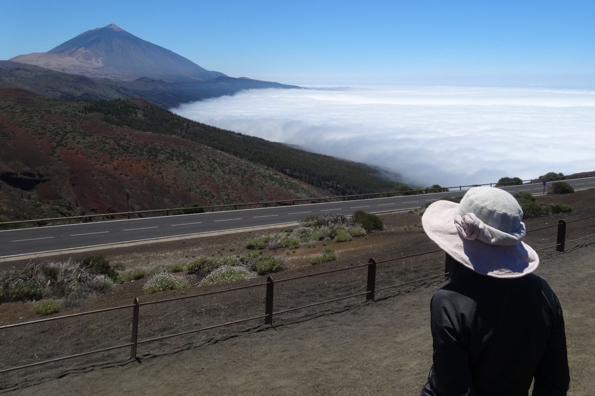 Person with a hat watching the Teide and the sea of clouds in Tenerife.