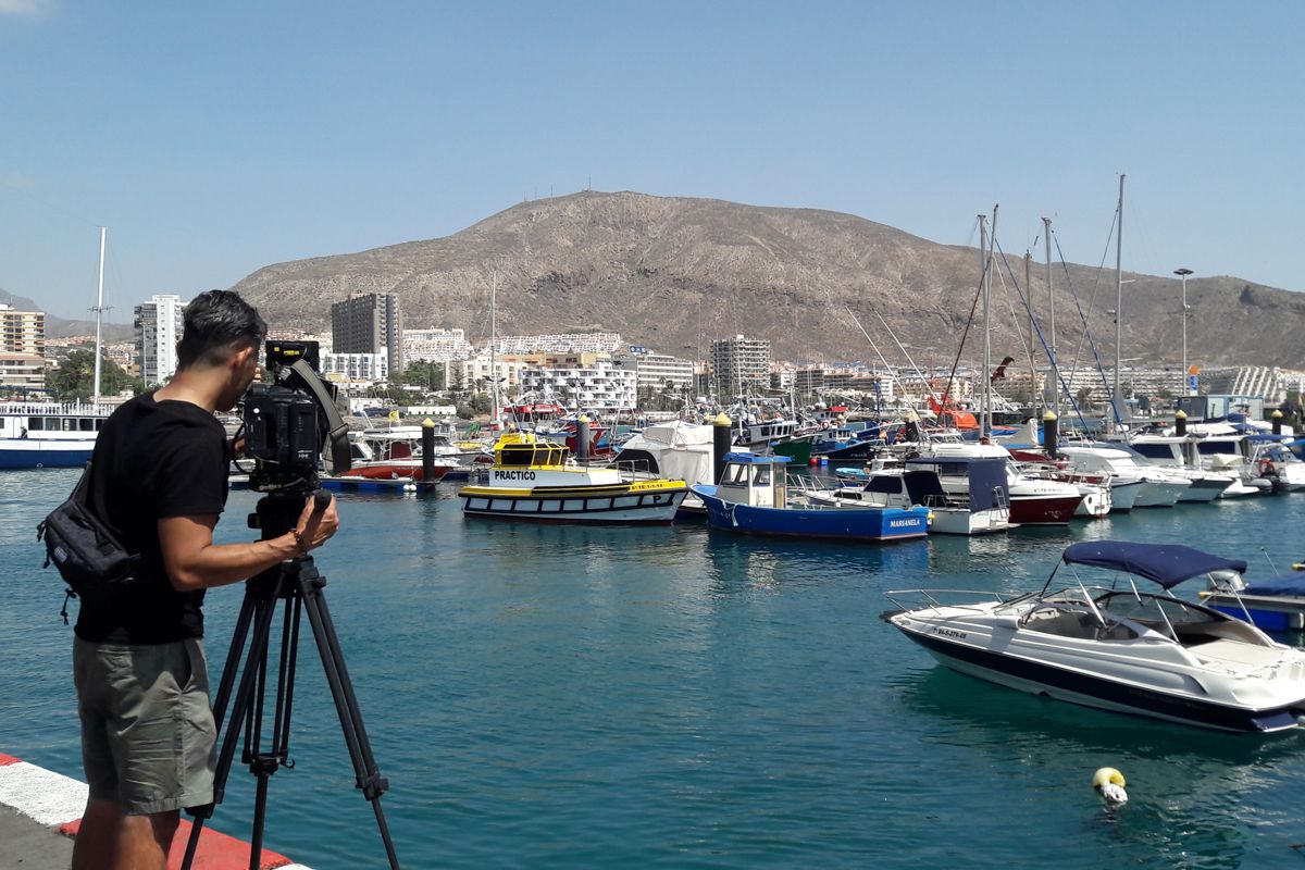 Cameraman filming boats in the port of Los Cristianos, Tenerife.