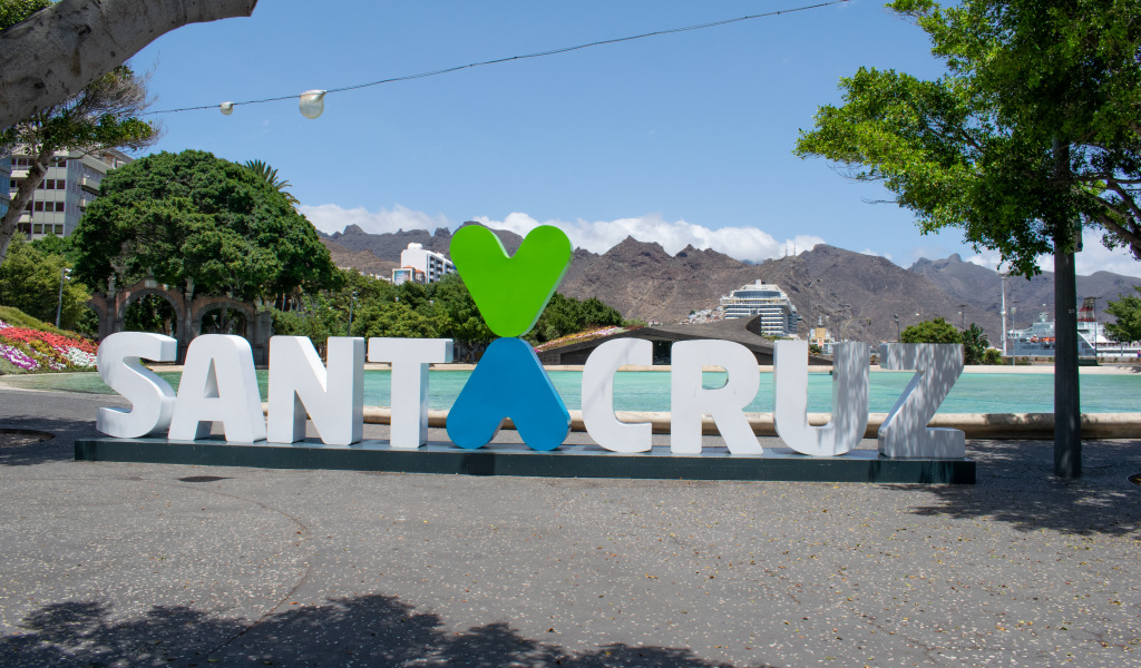 Santa Cruz sign in the square with trees and mountains in the background.