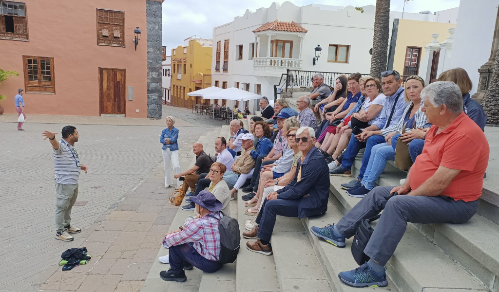 Group of tourists in a square in La Laguna, Tenerife, listening to a tour guide.
