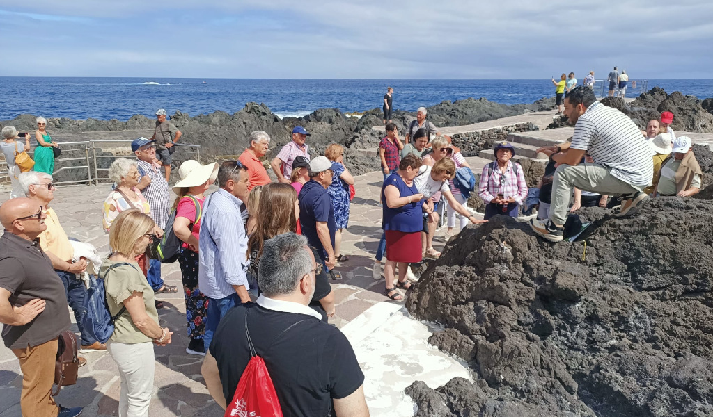 Group of people listen to a guide on volcanic rocks in Puerto de la Cruz, Tenerife.