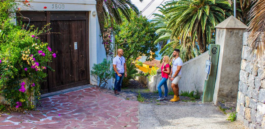 Three people talking on a street surrounded by palm trees in Tenerife.