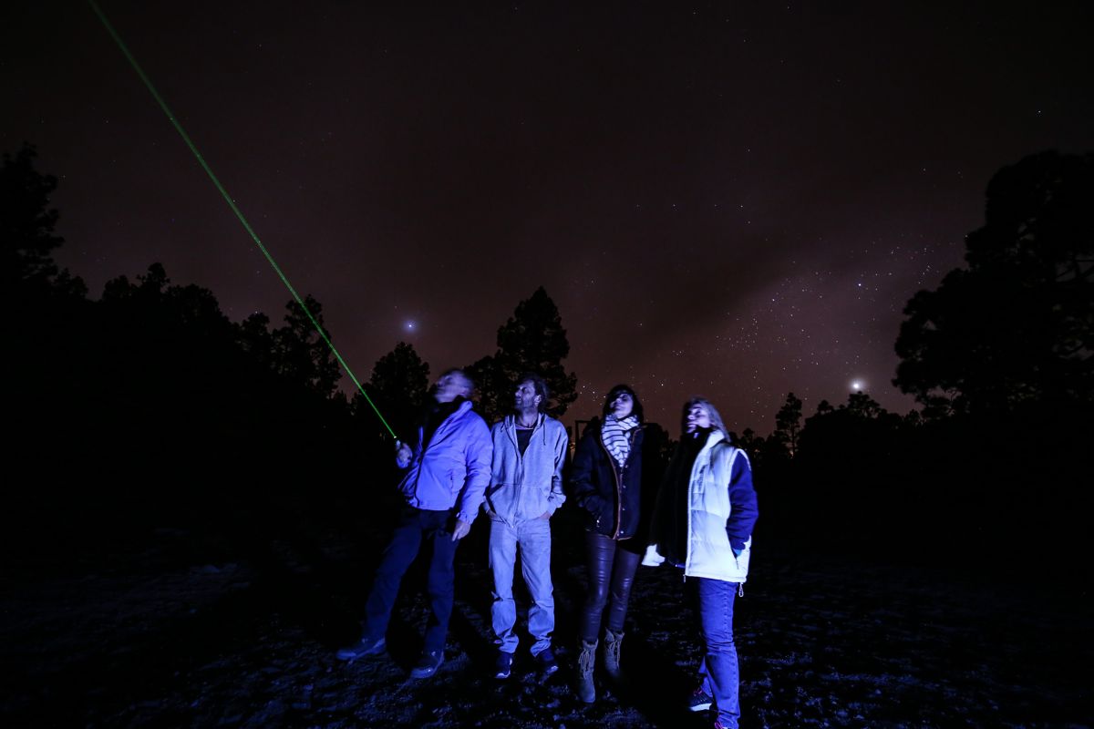 People observe the starry sky in Tenerife, a green laser point.