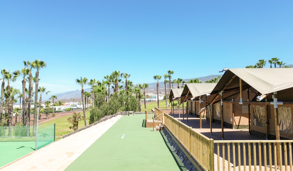Cabins next to palm trees and mountains in a complex in Tenerife.