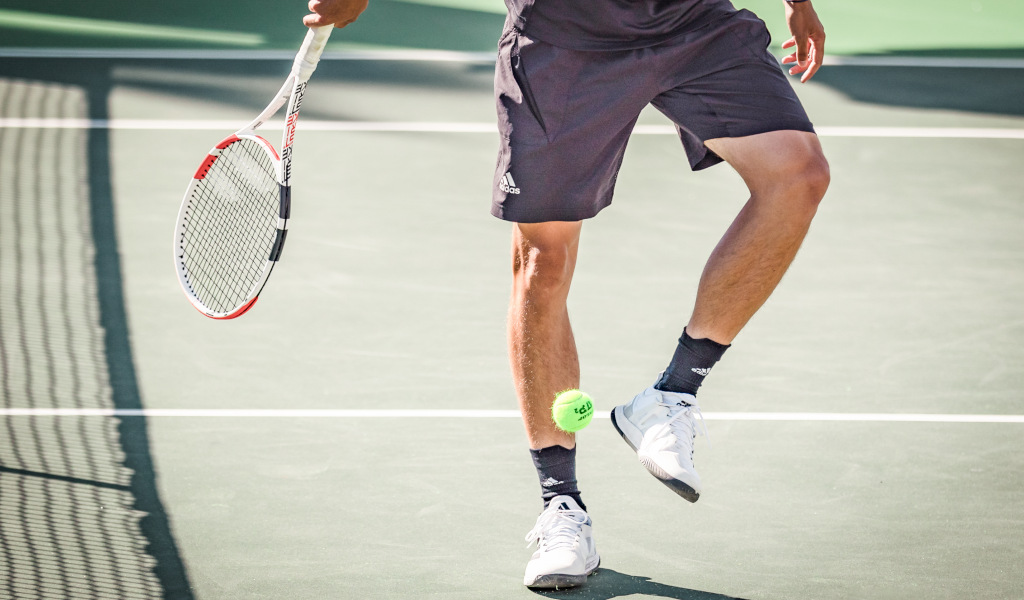 Tennis player on a court in Tenerife, hitting a ball with his racket.