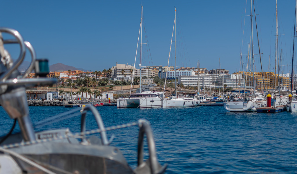 Marina in Costa Adeje, Tenerife, with yachts and buildings in the background.