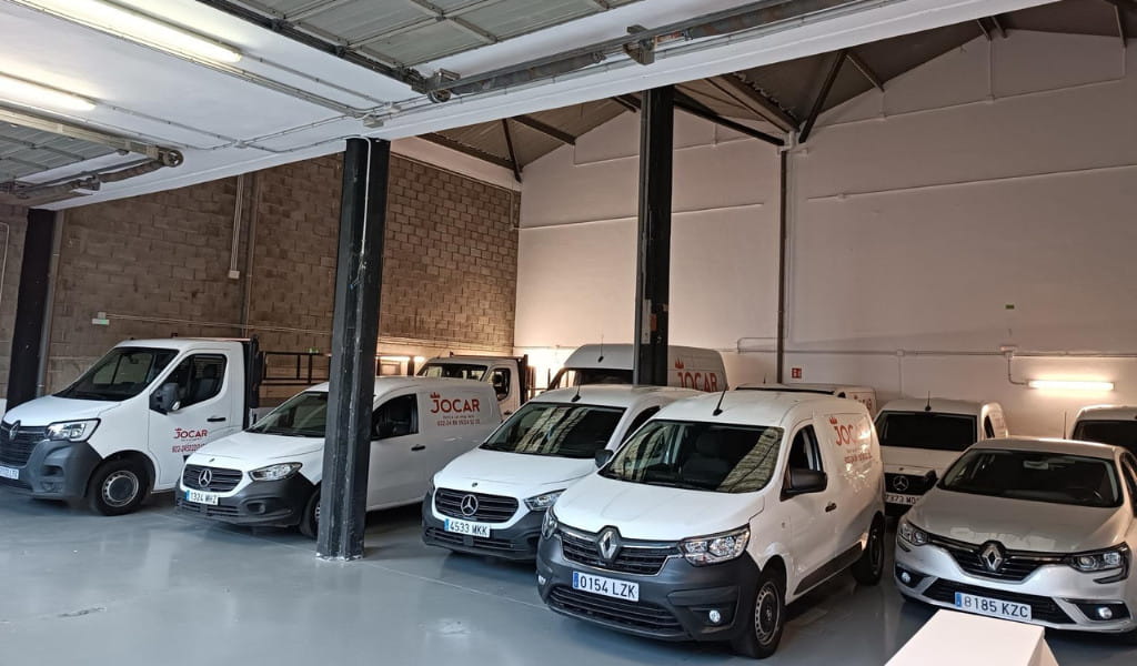 Delivery vehicles in a garage in Tenerife with the Jocar logo.
