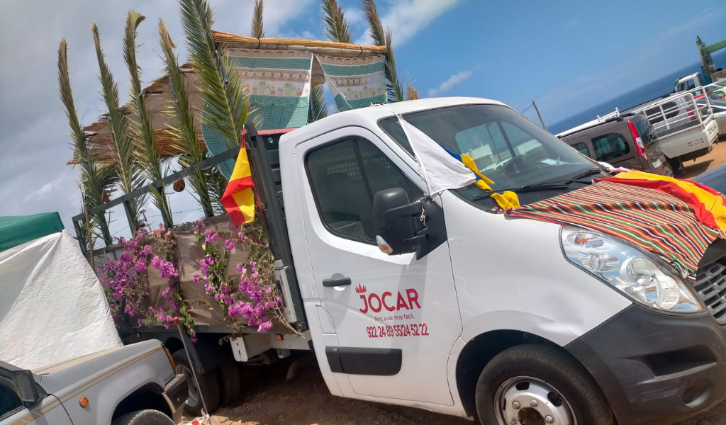 Truck decorated with flowers and flags in Tenerife, with partial sea view.