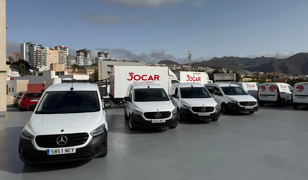 Parked Jocar vans in Santa Cruz de Tenerife, with buildings and mountains in the background.