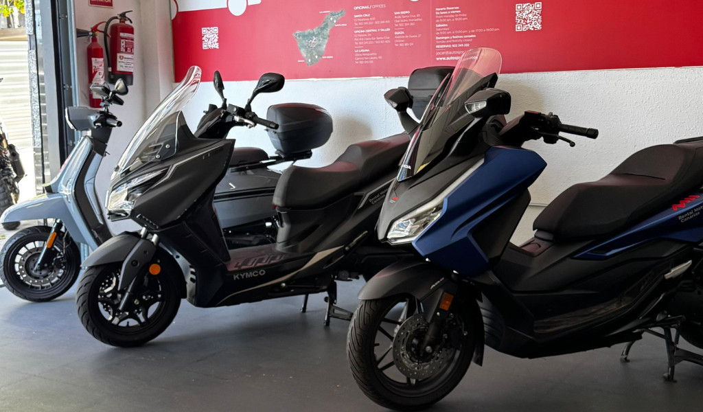 Kymco motorcycles on display, background with map of Tenerife and fire extinguishers.