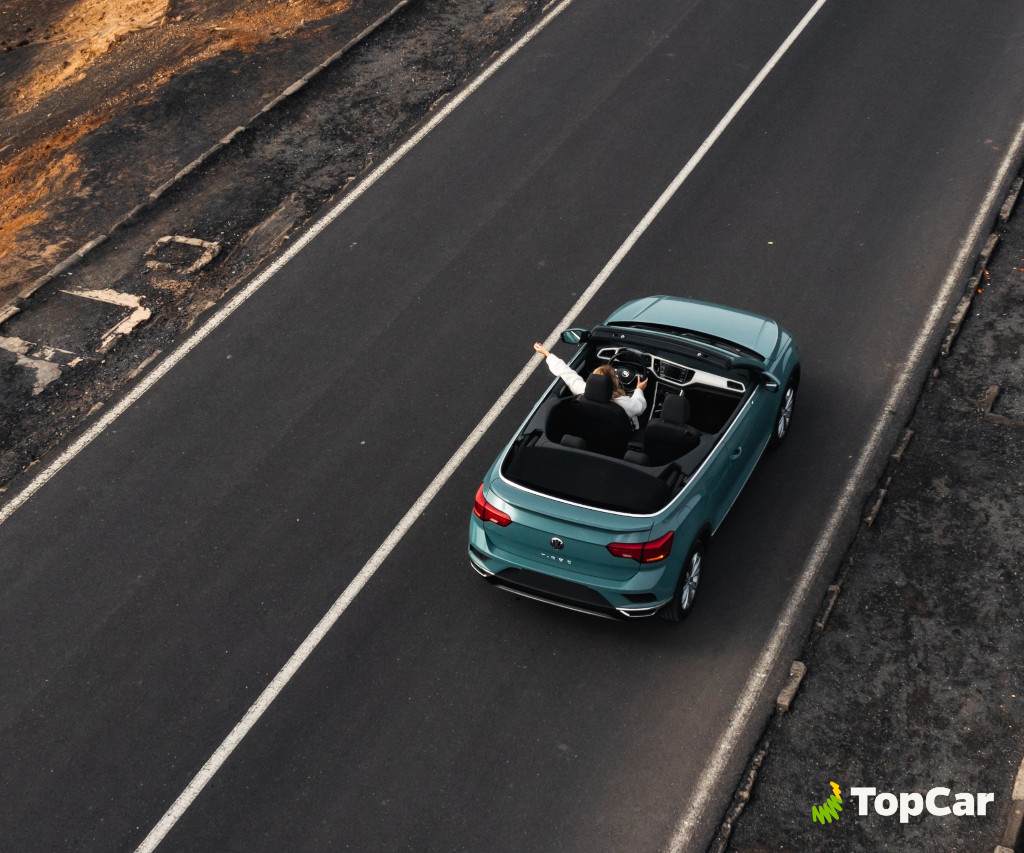 Person driving a blue convertible on the road in Tenerife. Visible text: TopCar.
