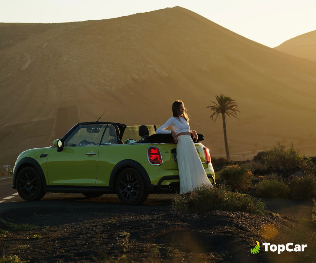 Green convertible car with person in front of mountainous landscape in Tenerife.