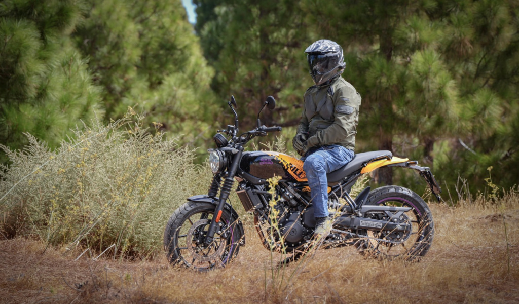 Person wearing a helmet sitting on a motorcycle on a forest road in Tenerife.