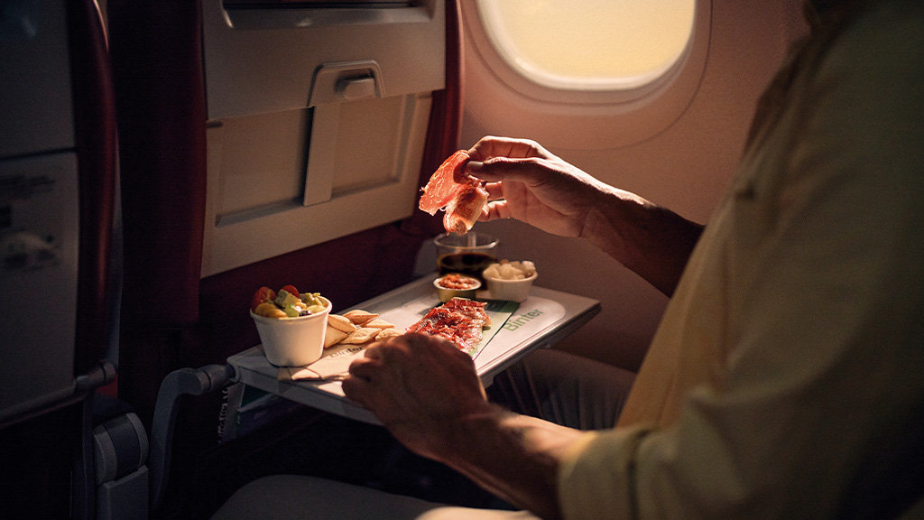 Person eating Serrano ham on a plane over Turner magazine.