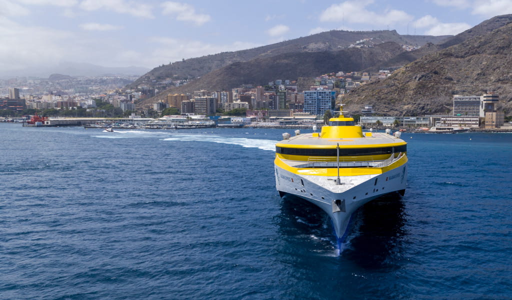 Yellow ferry in the port of Santa Cruz de Tenerife with the city in the background.
