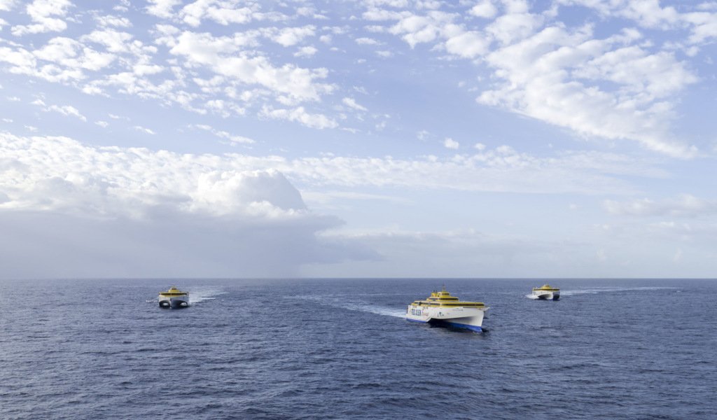 Three ferries in the ocean near Tenerife under cloudy skies.