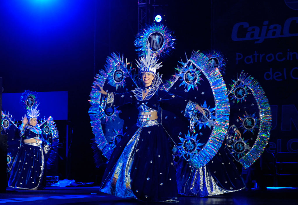 Women in bright fantasy costumes dancing on a stage in Tenerife.