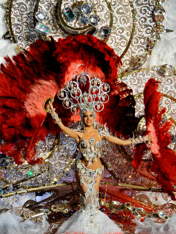 Carnival troupe in Tenerife with a bright costume and large red feathers.