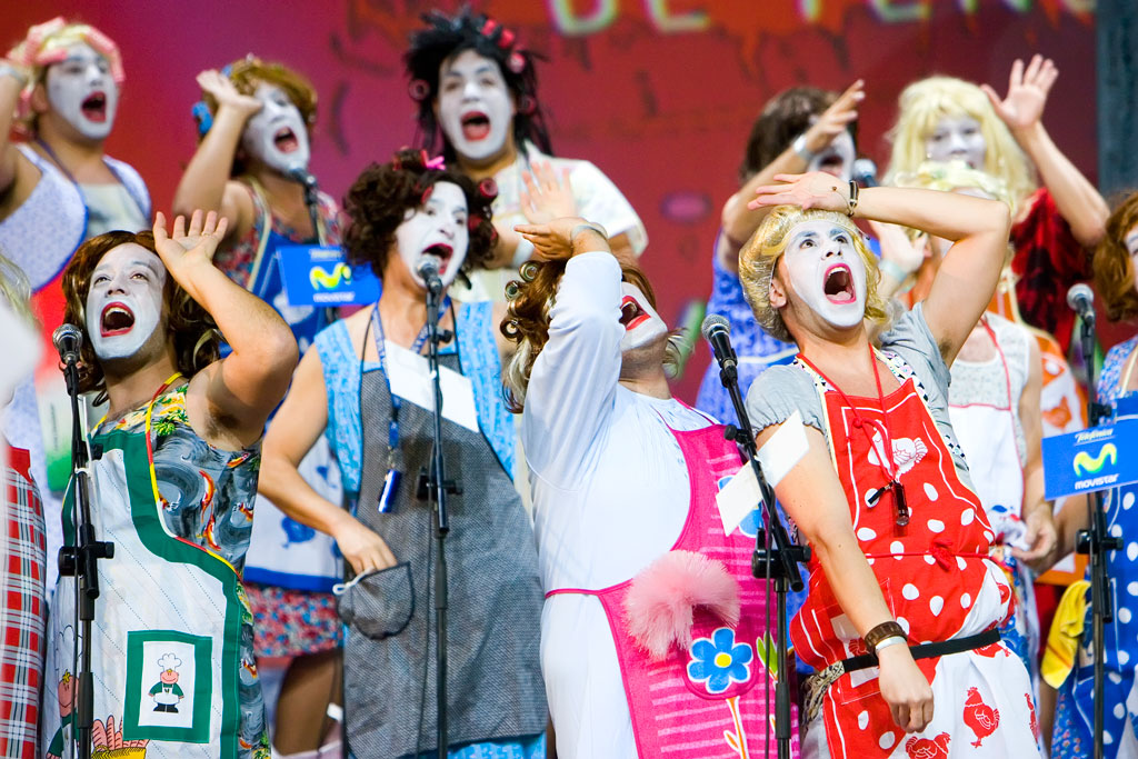 People in costumes and painted faces singing at an event in Tenerife.